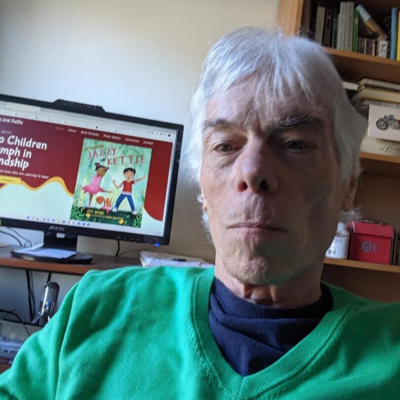 A man with white hair sitting in front of a computer screen.